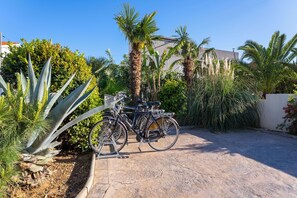 Une allée pavée, avec des vélos garés sur le côté, entourée de différentes plantes et d’arbres.