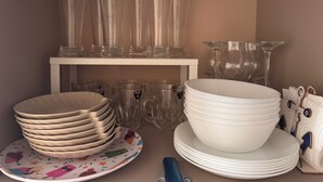 A storage area with clear glassware and plates, some with handles and others without, arranged on shelves and a table. - Klara Florenza (Hurghada)