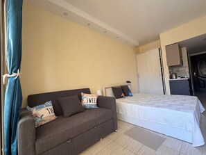Ein Schlafzimmer mit einem Bett, einem Schlafsofa und einer Küchenzeile.