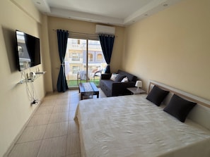 A hotel room with a bed, a sofa, a TV, and a window with curtains. - Klara Florenza (Hurghada)
