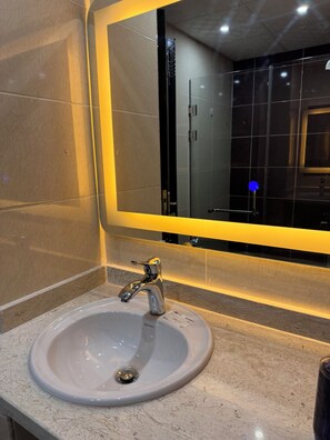 A bathroom with a round sink, a chrome faucet, and a mirror with a yellow light. - Klara Florenza (Hurghada)