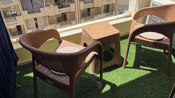 A balcony with artificial grass, wicker furniture, and a view of neighboring buildings. - Klara Florenza (Hurghada)