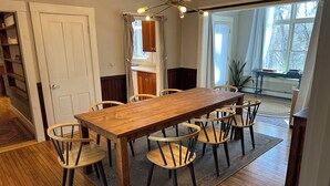 Un comedor con una mesa y sillas de madera, una araña y vistas al exterior a través de una ventana.