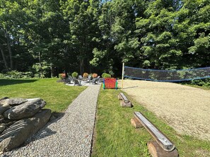 A backyard with a patio area, a volleyball net, and a fire pit. - NEW! Former gorgeous B&B 9 sleeping rooms, 4.5 baths, BIG hot tub, BEST location (Bethel)