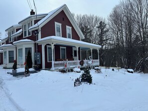 Ein zweistöckiges Haus mit Veranda, umgeben von Schnee.