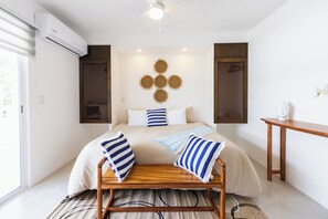 A modern bedroom with a bed, bedside tables, a bench, and a wall-mounted light fixture. - Nature, Tranquility, and the Beach (Tulum)