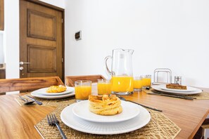 A breakfast setting with plates of pastries, glasses of orange juice, and a pitcher of juice on a wooden table. - Nature, Tranquility, and the Beach (Tulum)