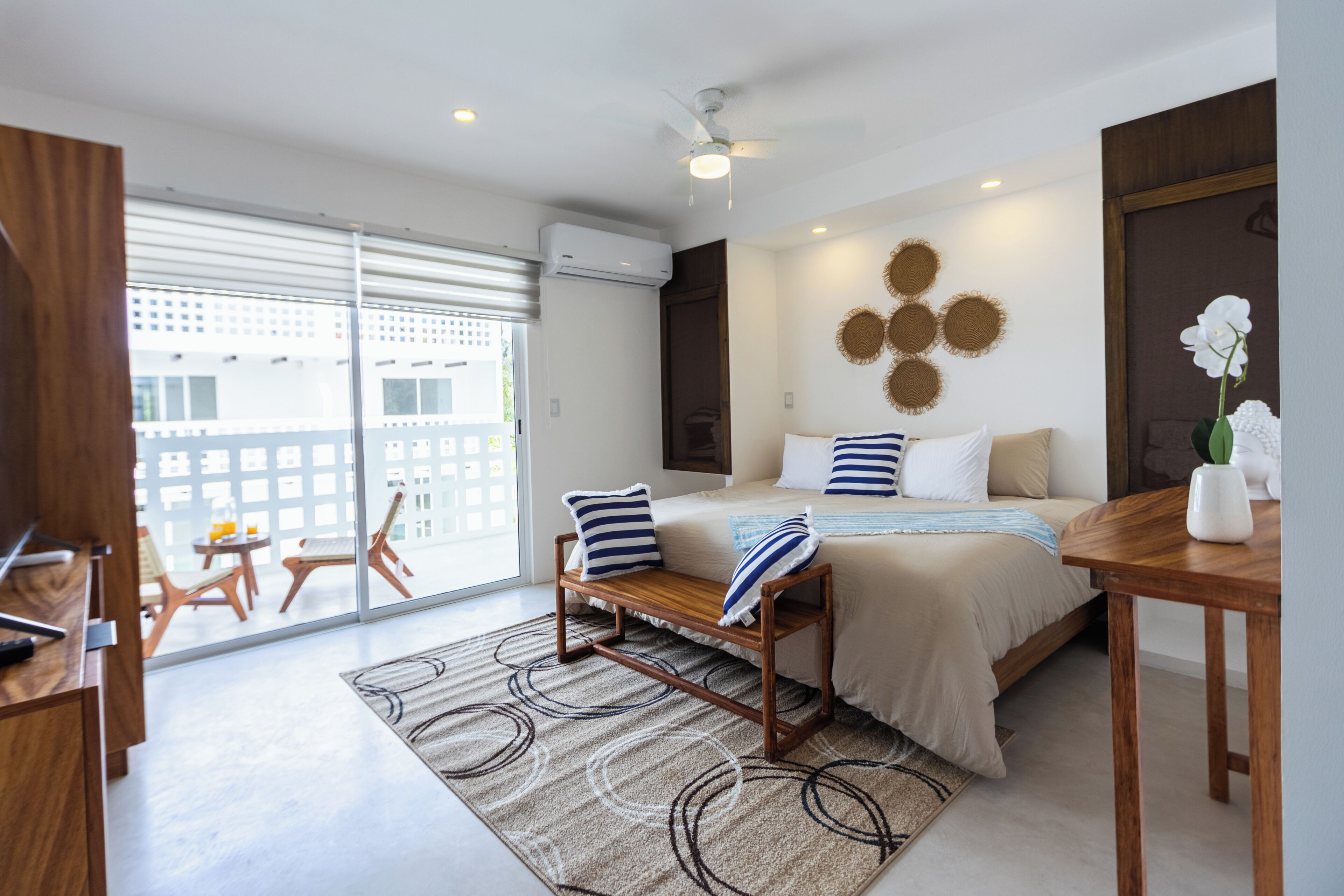 Quarto moderno com cama, mesa de cabeceira e vista para o exterior.
