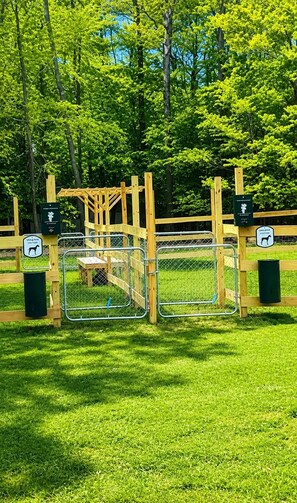 A fenced area with a wooden structure, a bench, and informational signs. - Pocono Pines Retreat Hot Tub & Cozy Escape in PCP (Tobyhanna)