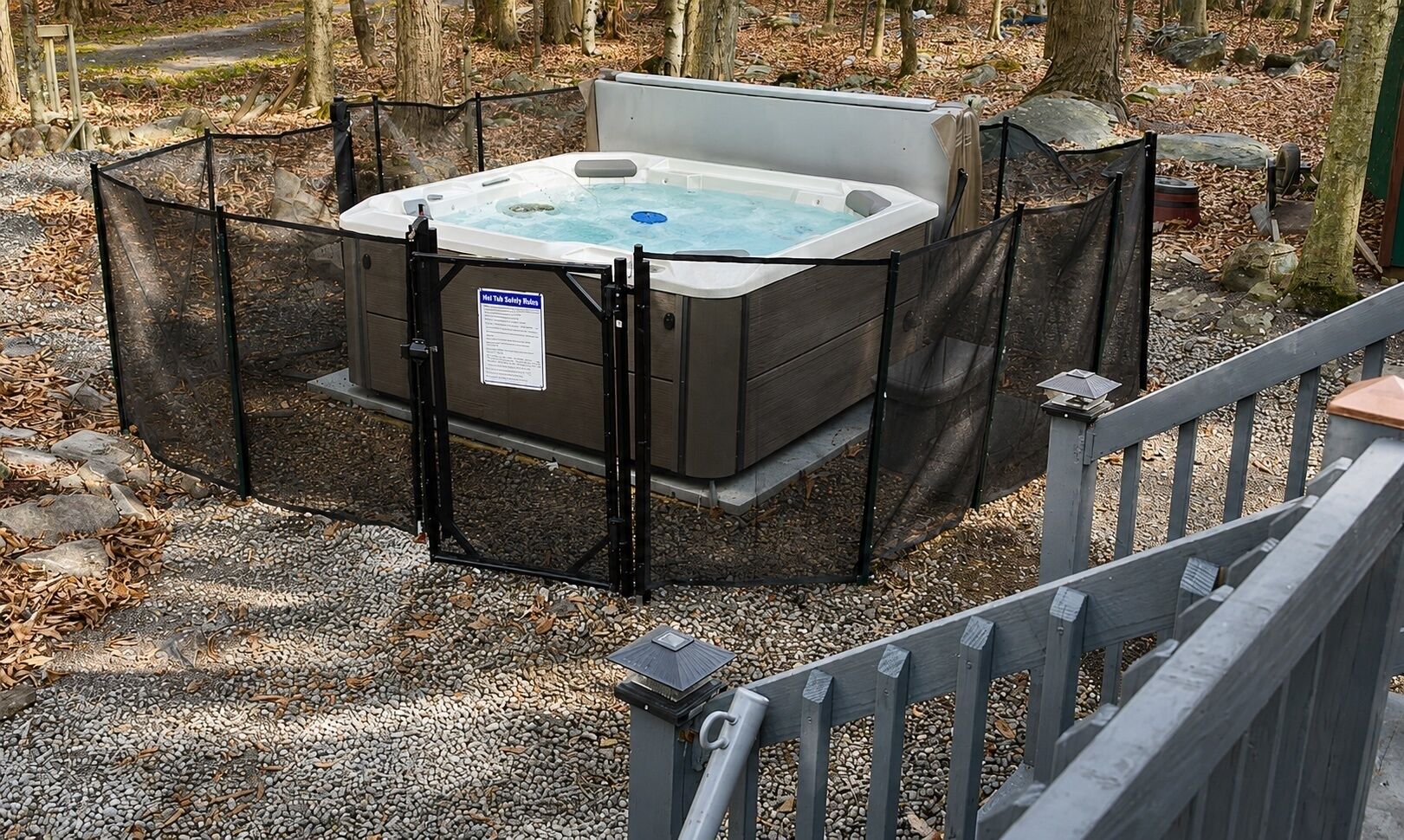 A hot tub surrounded by a metal fence, with a sign indicating safety rules.