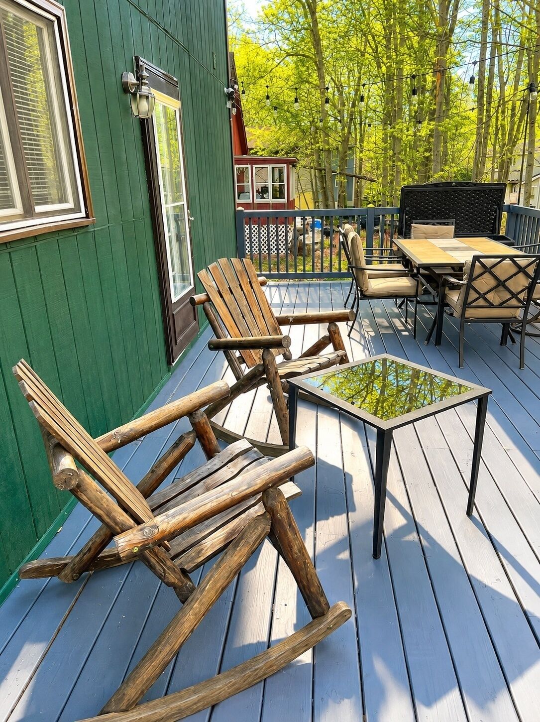 A wooden deck with outdoor furniture, including a rocking chair and a table with chairs.