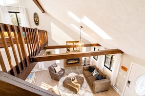 A spacious loft-style living area with a fireplace, wooden beams, and a high ceiling. - Pocono Pines Retreat Hot Tub & Cozy Escape in PCP (Tobyhanna)