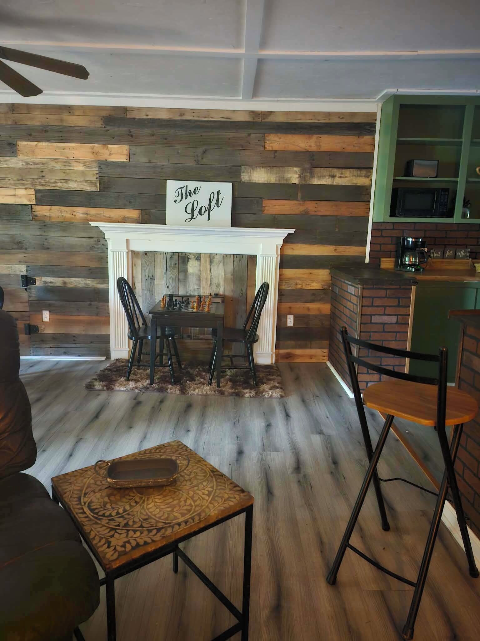 A cozy living room with a fireplace, a chessboard, and a coffee station.