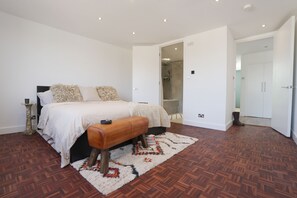Ein Schlafzimmer mit einem Bett, einer Sitzbank, einem Teppich und einer Duschkabine.