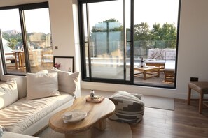 A modern living room with a sofa, a wooden coffee table, and a view through large windows. - Luxury 3 Bedrooms 4 Bathrooms Penthouse Roof Terrace With Parking (London)