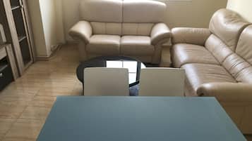 Una sala de estar con sofá, mesa de centro y mueble para televisión.