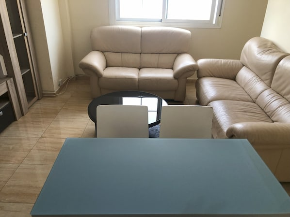 Una sala de estar con sofá, mesa de centro y mueble para televisión.
