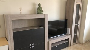 Una sala de estar moderna con un televisor de pantalla plana, mueble de entretenimiento de madera y un armario con cajones.