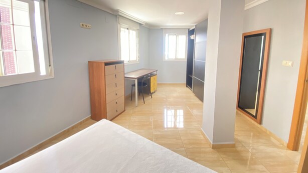Una habitación con una cama, un escritorio y un armario.