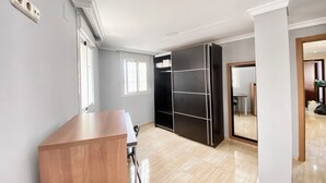 Una habitación con un escritorio de madera, un armario negro, una ventana y una puerta que da a otra estancia.