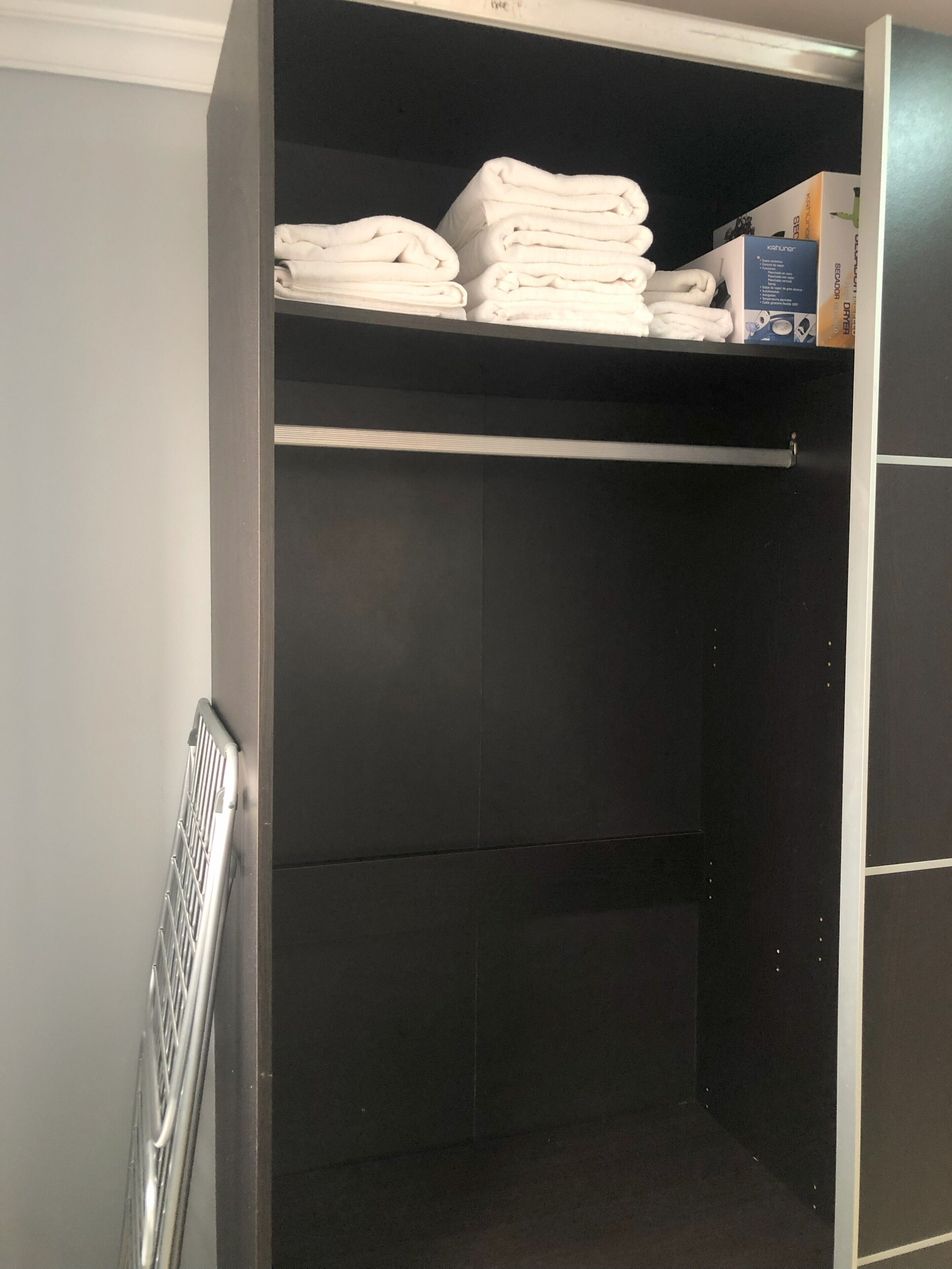 A storage closet with shelves holding folded towels and a box on top.