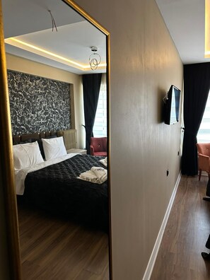 Ein Hotelzimmer mit einem Bett, einem an der Wand befestigten Flachbildfernseher und Holzboden.