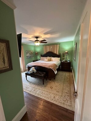 A bedroom with a bed, a nightstand, a bench, a ceiling fan, and a rug. - Beautiful historic home w/view of Kennebec River (Bath)
