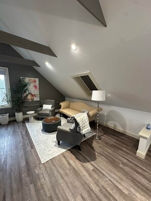 Ett vardagsrum i loftstil med en soffa, en pall och en lampa.