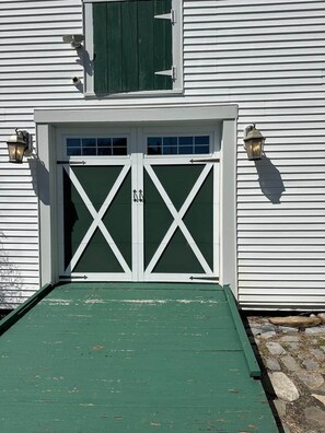 A white building with a green door and windows, a ramp leading to the entrance, and two wall-mounted lanterns. - Beautiful historic home w/view of Kennebec River (Bath)
