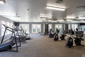 Ein Fitnessstudio mit Laufbändern, Crosstrainern und Gewichten.
