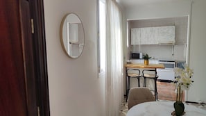 Une cuisine moderne avec des meubles blancs, un four à micro-ondes et un coin repas comprenant deux chaises et une table.