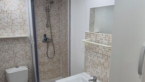 Un baño con inodoro, ducha y lavamanos.