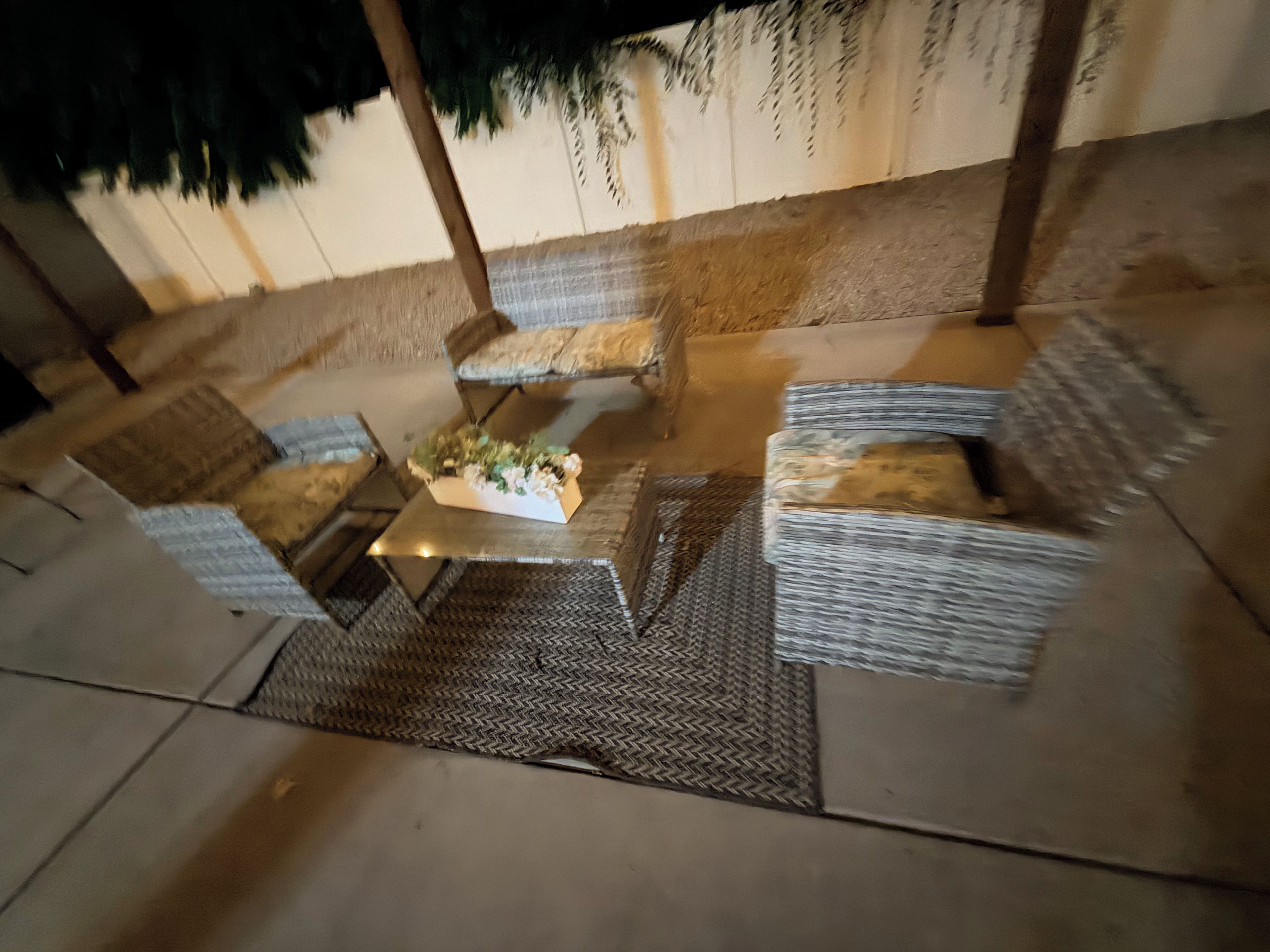 An outdoor seating area with wicker furniture and a central table.
