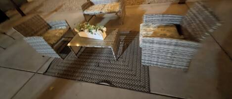 An outdoor seating area with wicker furniture and a central table.