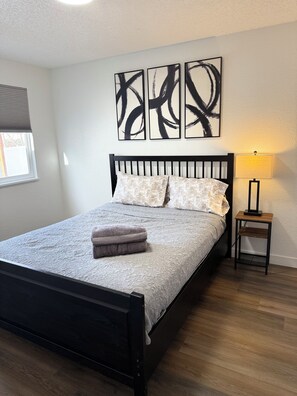 A bedroom with a bed, a nightstand, a lamp, and abstract wall art. - Modern Home/ Near DIA & Anschutz Medical Campus (Denver)