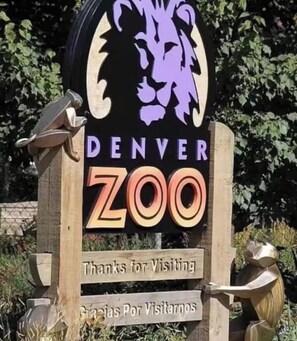 Schild am Eingang eines Zoos mit einer Löwen-Silhouette, der Aufschrift 'DENVER ZOO' und einer zweisprachigen Meldung 'Danke für Ihren Besuch'.