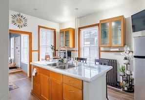 A modern kitchen with wooden cabinets, a central island, and a built-in oven. - Spacious Historical Oasis (Allentown)