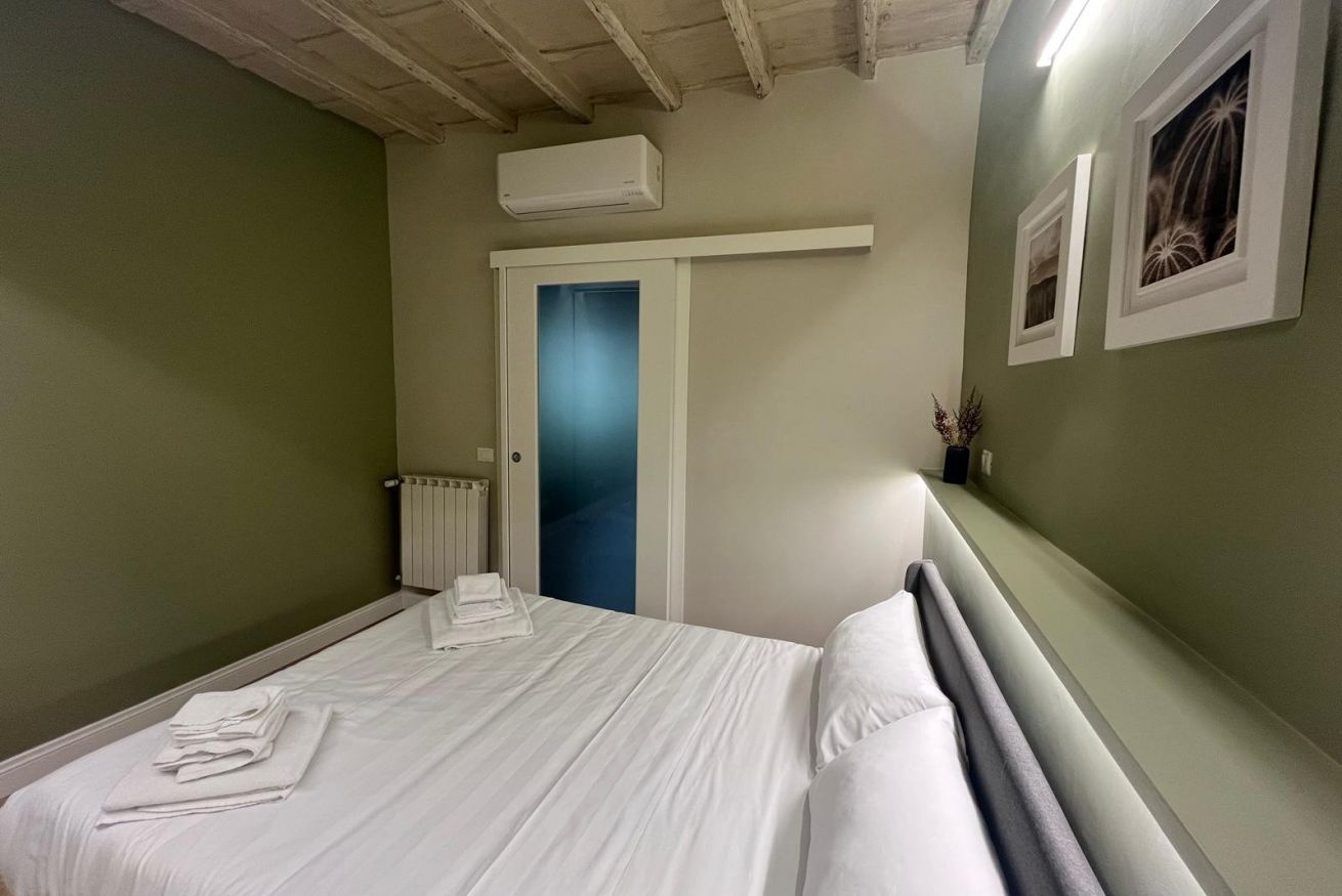 Habitación de hotel con cama, radiador, puerta y aire acondicionado instalado en la pared.