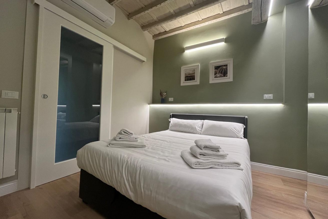 A bedroom with a bed, a door, and a wall-mounted light fixture.