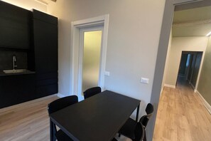 Eine moderne Küche mit schwarzen Schränken und einer Essecke mit dunklem Tisch und Stühlen.