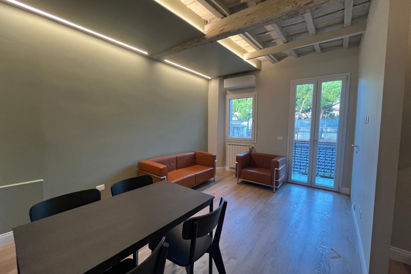 Une pièce comprenant une table à manger, deux canapés et une porte-fenêtre coulissante donnant sur un espace extérieur.