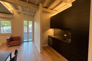 Eine moderne Küche mit dunklen Schränken, einer Edelstahl-Spüle und einem Fenster mit Blick auf einen Balkon.