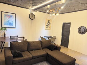 A modern living space with a sectional sofa, a dining table, and a small round table. - City Centre Oasis (Accra)