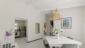 Ett modernt kök med ett kylskåp, ett matbord med stolar och en hängande lampa.