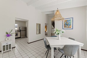Eine moderne Küche mit Kühlschrank, einem Esstisch mit Stühlen und einer Hängelampe.