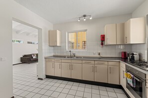 A modern kitchen with a central island, a built-in oven, and a gas stove. - Villa Cuartillo | Spacious 8-person villa with a private pool (Willemstad)
