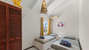 A room with two beds, a wardrobe, a window with curtains, a ceiling light, and a wall-mounted air conditioner.