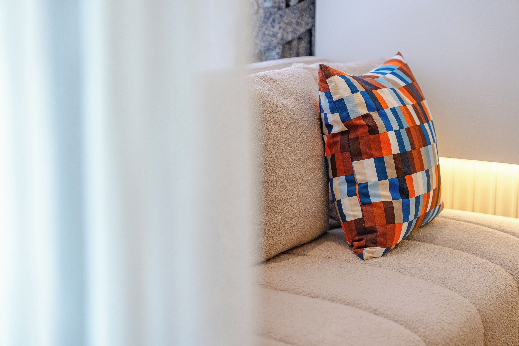 A beige sofa with a patterned pillow.