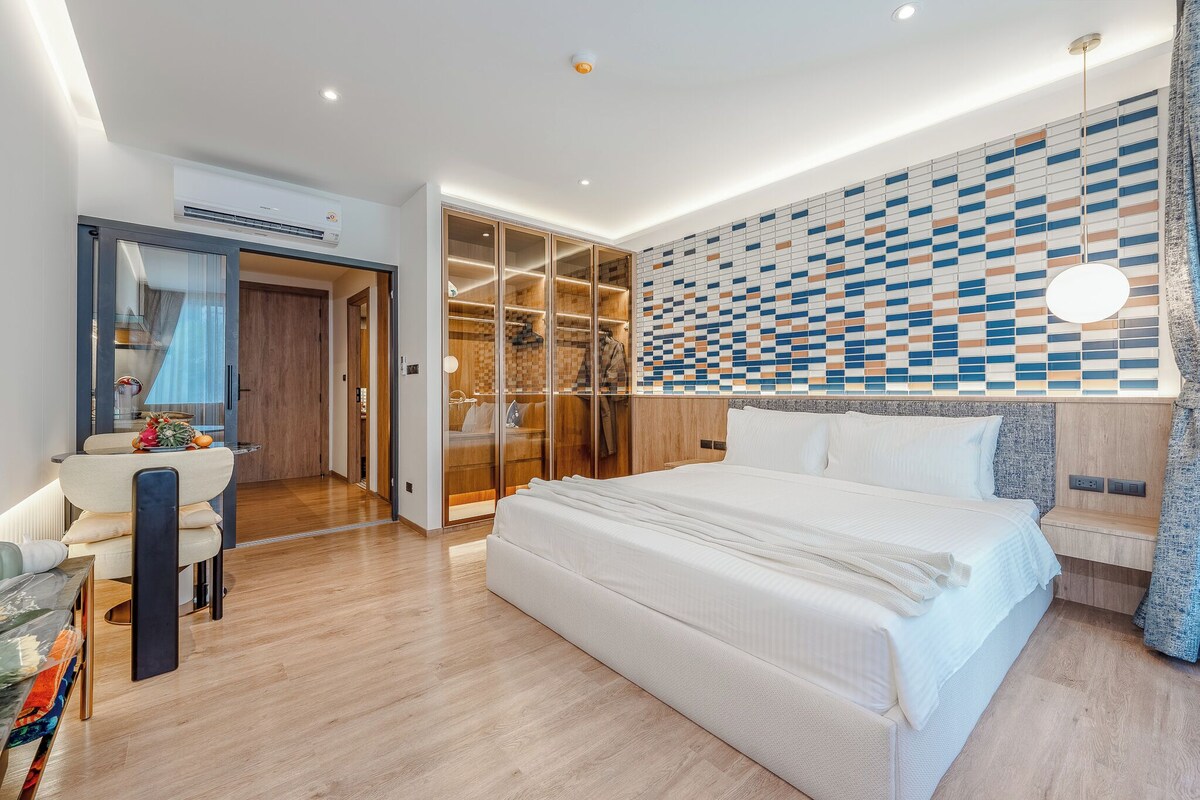 A modern bedroom with a large bed, a walk-in closet, and a patterned wall.
