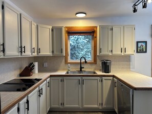 A modern kitchen with white cabinets, a built-in stove, a sink, and a window with a view of snow-covered trees. - Mont-Tremblant Escape:Cozy Fireplace & Hot Tub
Entire Home
Sleeps 6
Pet Friendly (Mont-Tremblant)
